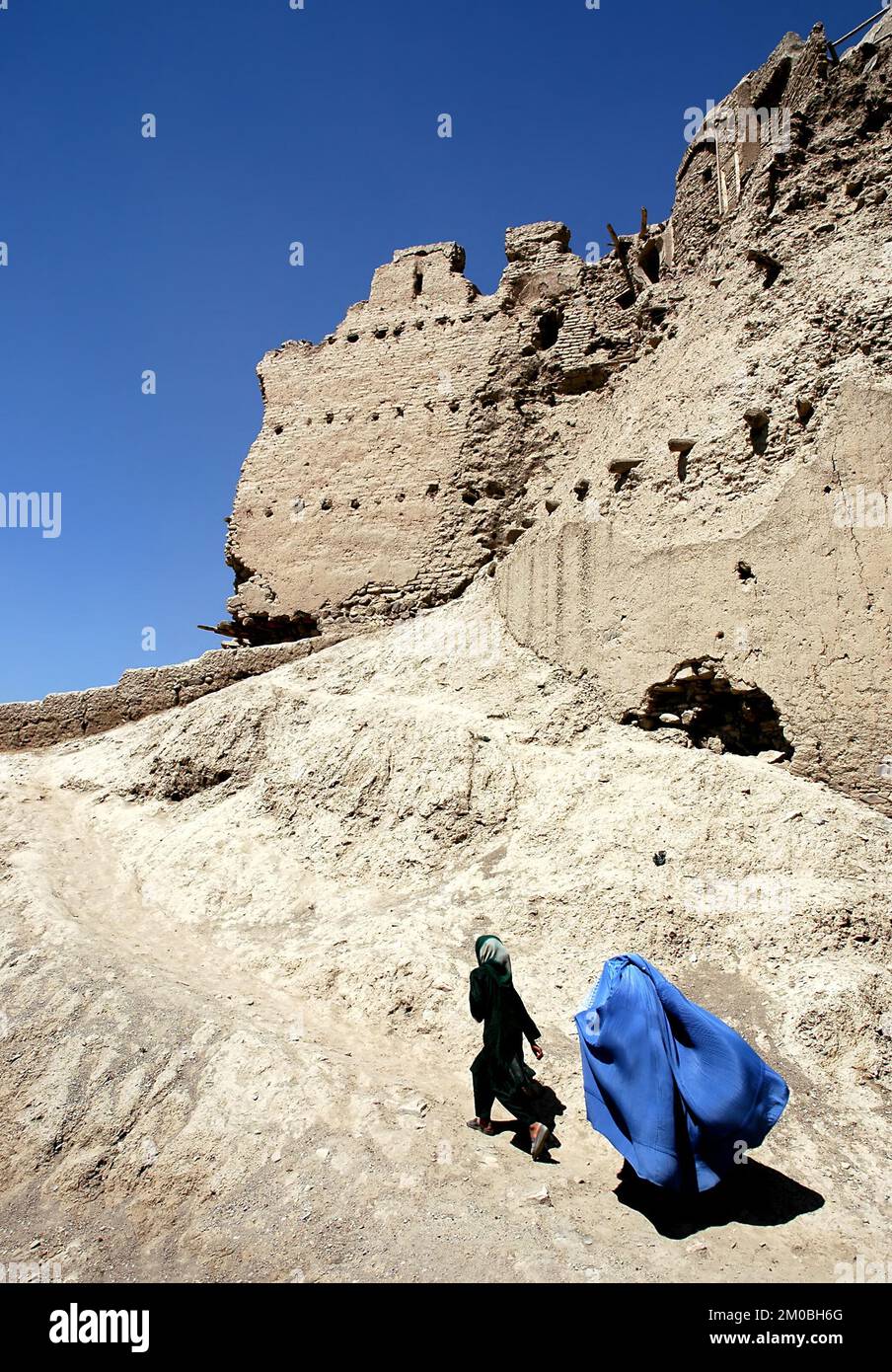 Ein Mädchen und eine Frau gehen über die Mauer der Zitadelle Ghazni in Ghazni, Afghanistan. Die Frau trägt eine blaue Burka (Burka), traditionell in Zentralafghanistan Stockfoto