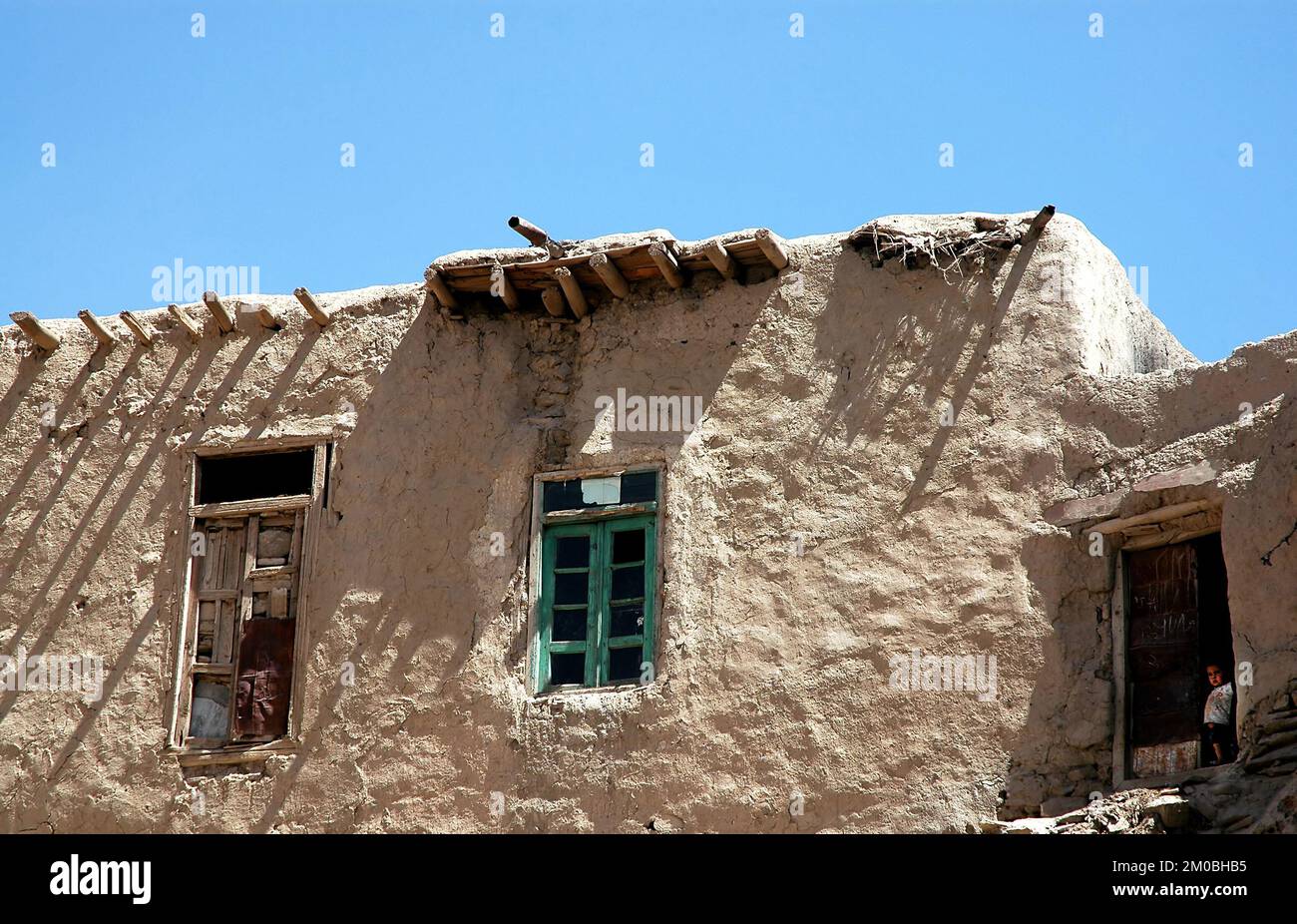 Ghazni/Afghanistan: Ein kleines afghanisches Kind schaut von einer Tür in einem traditionellen Haus in Ghazni aus. Stockfoto