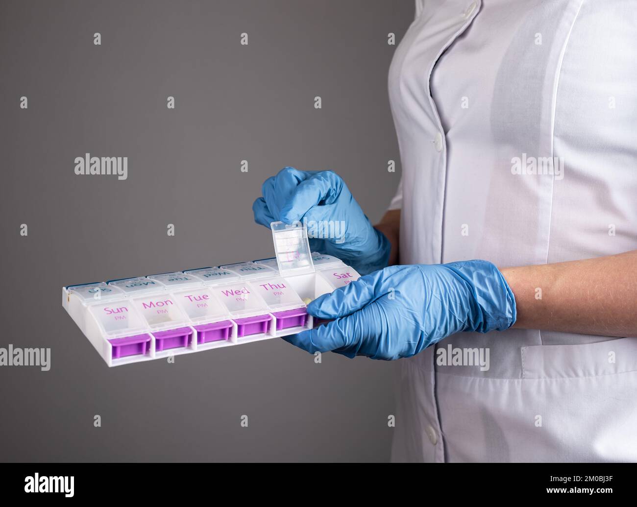 Pharmazie-Konzept. Tablettenhülle, Tablettenorganisator, Vitaminbox in Arzthänden-Nahaufnahme. Hochwertiges Foto Stockfoto