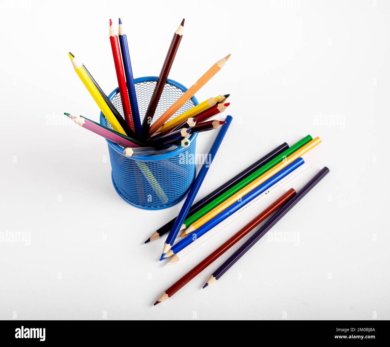 Farbige Bleistifte sind in Büromaschinen aus Metall verstreut und außerhalb des Bürokorbs verstreut. Chaos in Kunstgütern. Hochwertiges Foto Stockfoto
