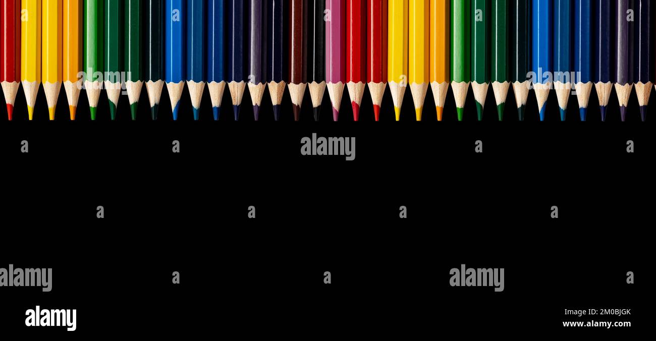 Farbige Bleistifte auf schwarzem Hintergrund. Promo-Banner mit Kopierbereich für Text, mehrfarbige Kunstmaterialien. Werbung für die Malschule. Hochwertiges Foto Stockfoto