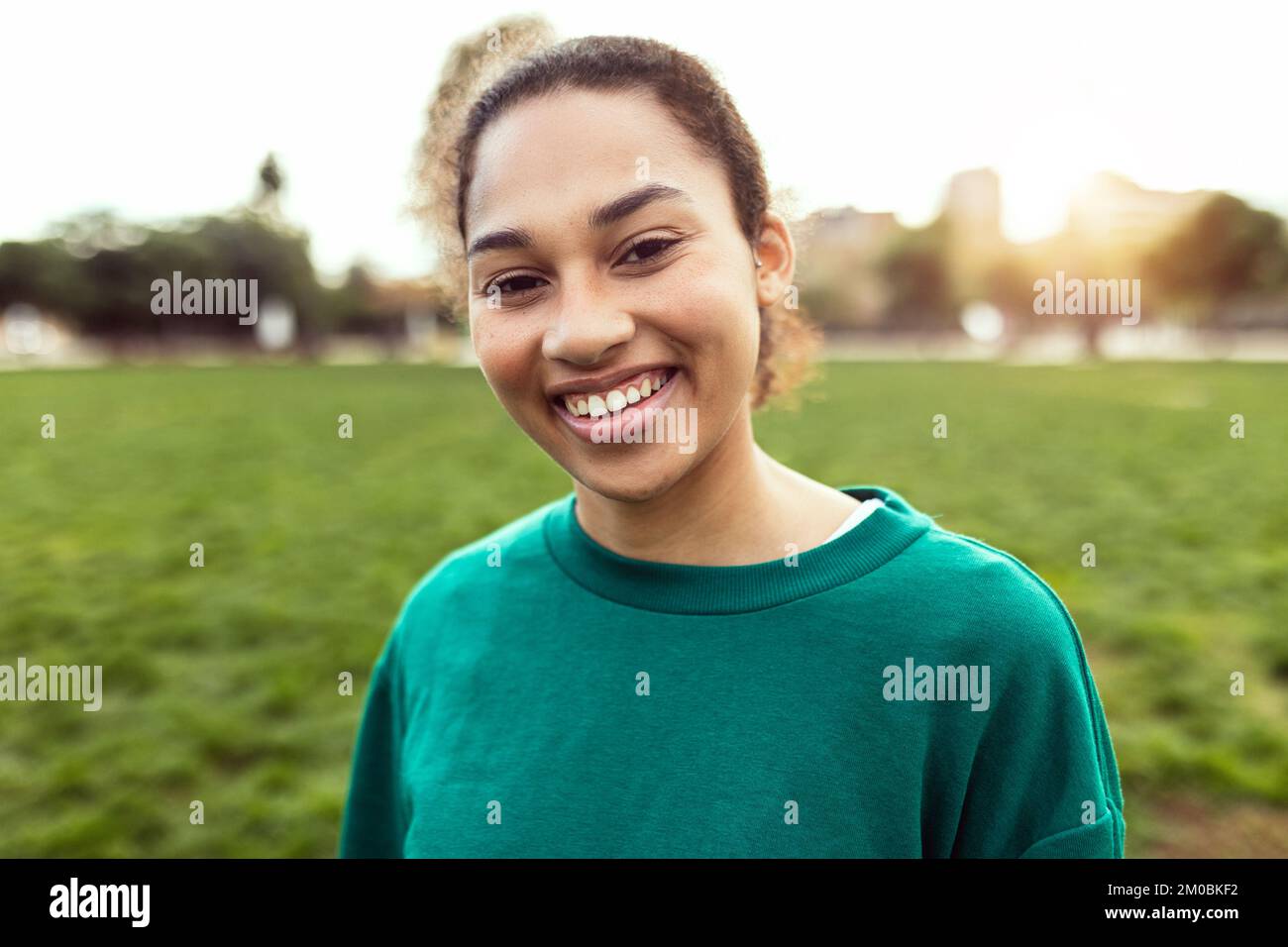Junge lateinamerikanische Frau, die draußen vor der Kamera lächelt Stockfoto