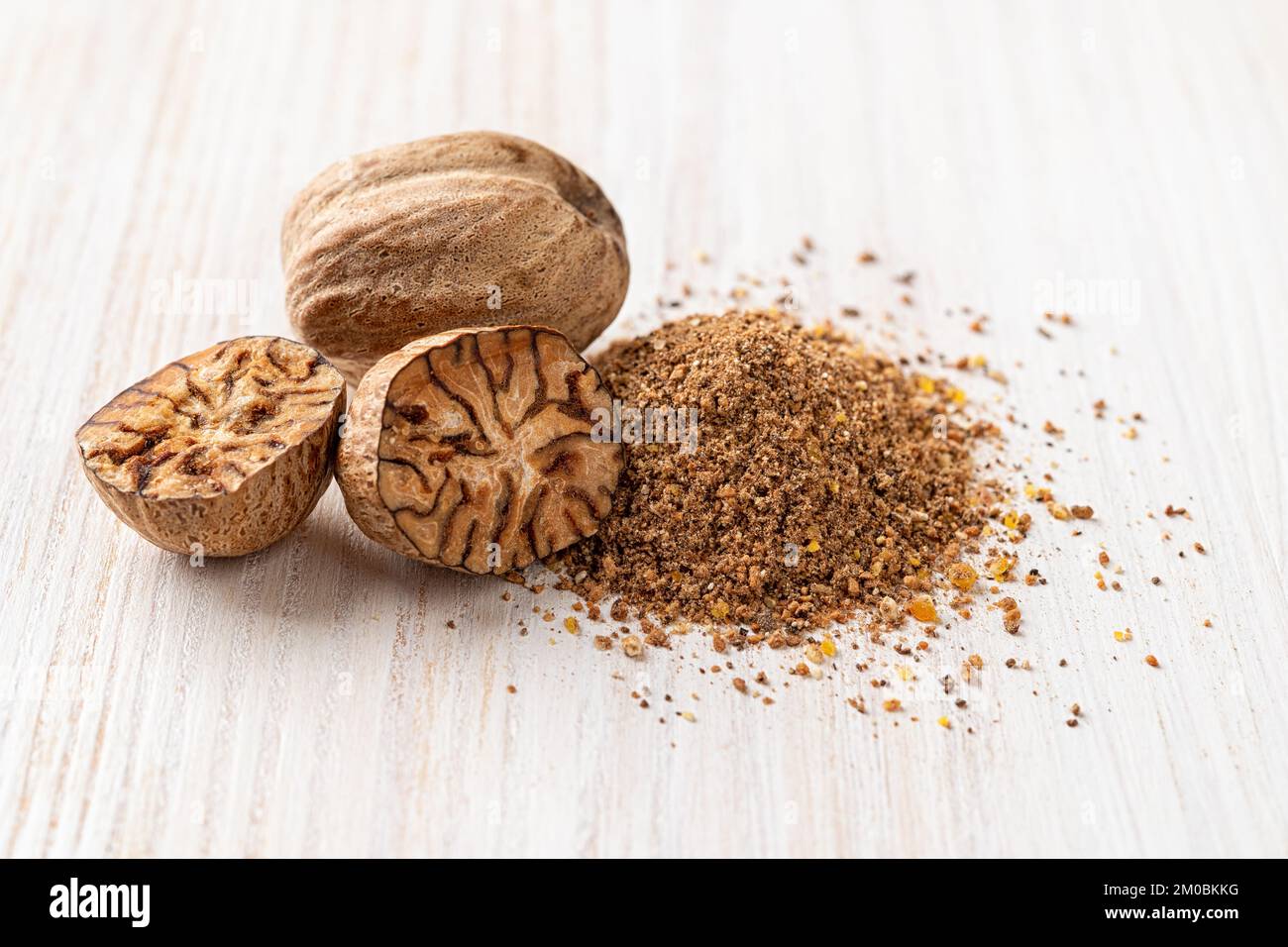 Ganze, halbierte und geriebene Muskatnusssamen auf einem weißen Holztisch. Gewürze und Gewürze. Geschliffene muskatnuss. Organische Früchte des Myristica-Duftbaums. Stockfoto