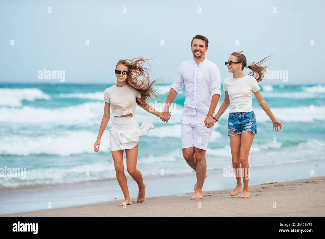 Glücklicher Vater und seine entzückende kleine Töchter am tropischen Strand Spaß Stockfoto