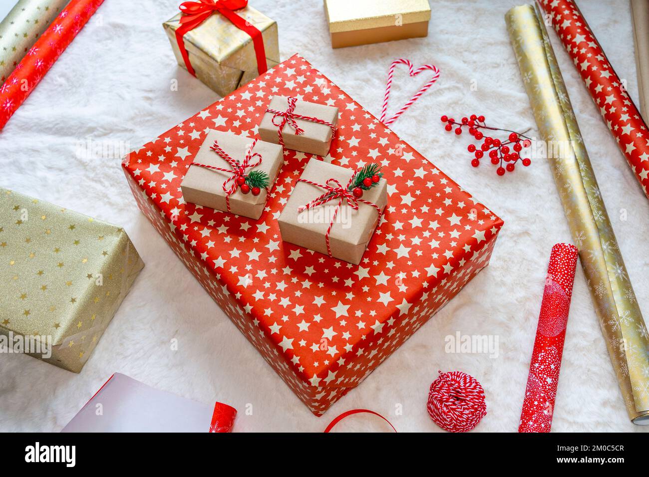 Weihnachtsgeschenkpakete auf dem Teppich im Wohnzimmer vorbereiten Stockfoto