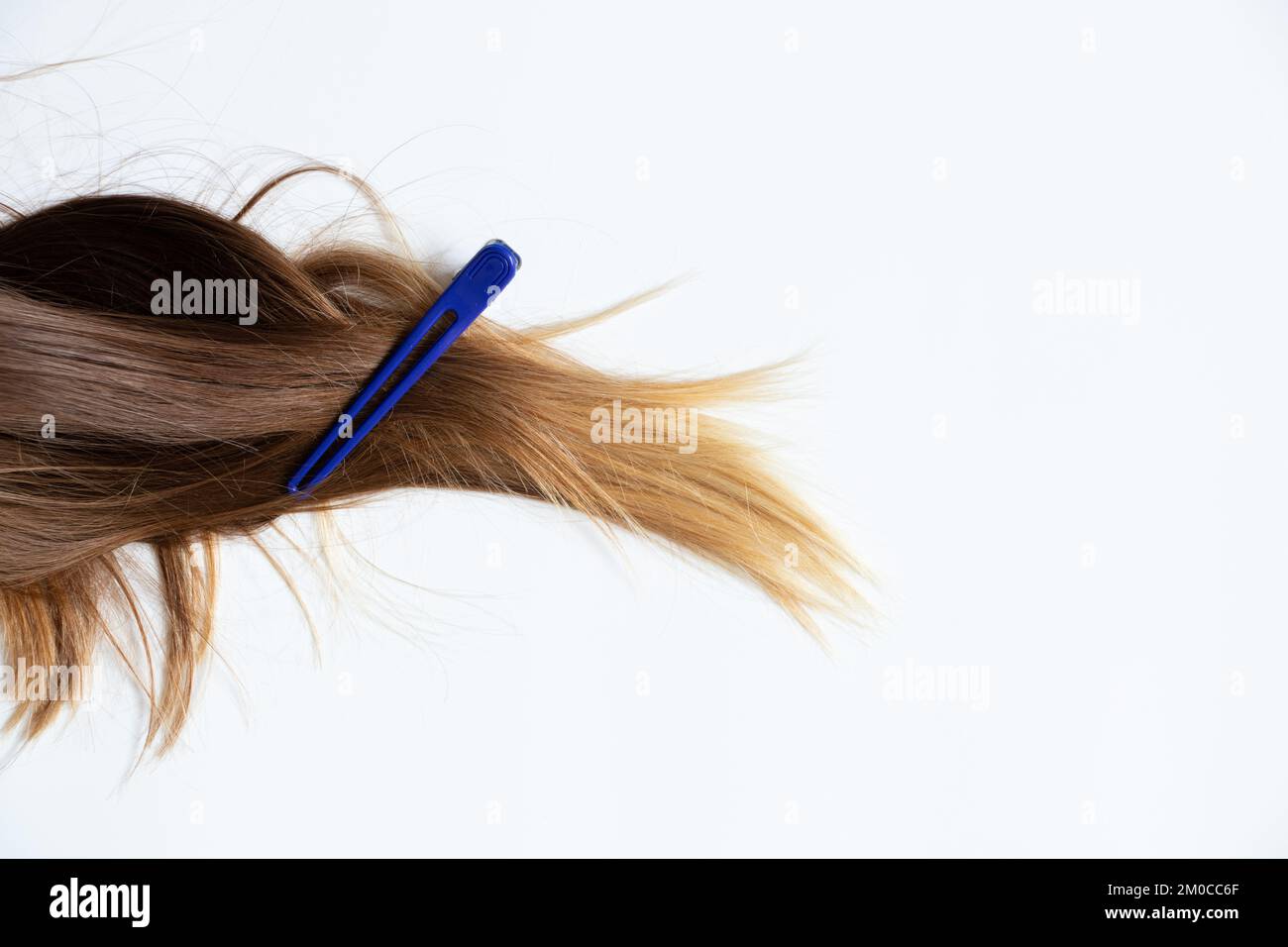 Festgeklebte weibliche Haare liegen auf weißem Hintergrund, ein Clip am Haar, ein Friseur Stockfoto