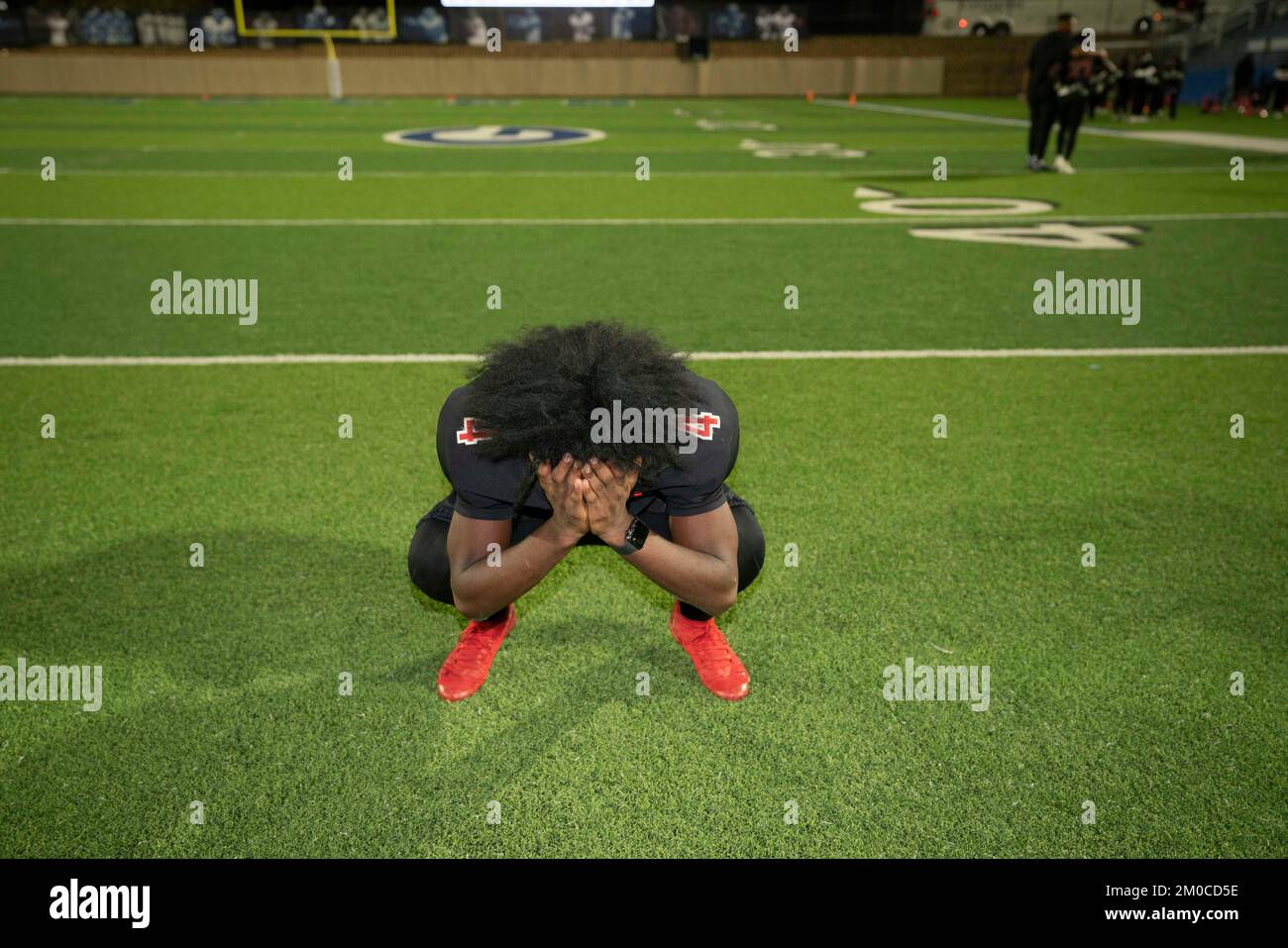 Georgetown Texas, USA, Dezember 3 2022: Ein enttäuschter Fußballspieler bedeckt sein Gesicht nach dem Verlust seines Teams bei einem Viertelfinalspiel der University Scholastic League (UIL) im Playoff in Zentral-Texas. ©Bob Daemmrich Stockfoto