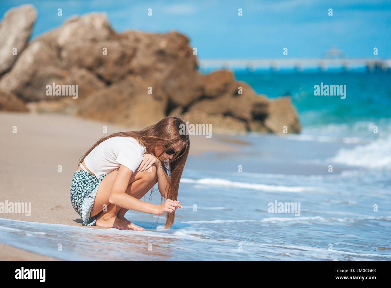 Ein bezauberndes Teenager-Mädchen sammelt Muscheln am Strand Stockfoto