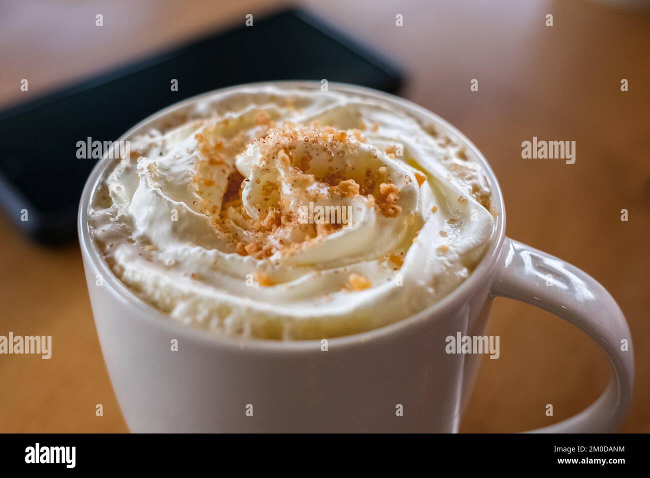 Kaffee Karamell Latte weiße Tasse auf dem Tisch. Morgenkaffee zum Frühstück. Niemand, verschwommen, selektiver Fokus Stockfoto