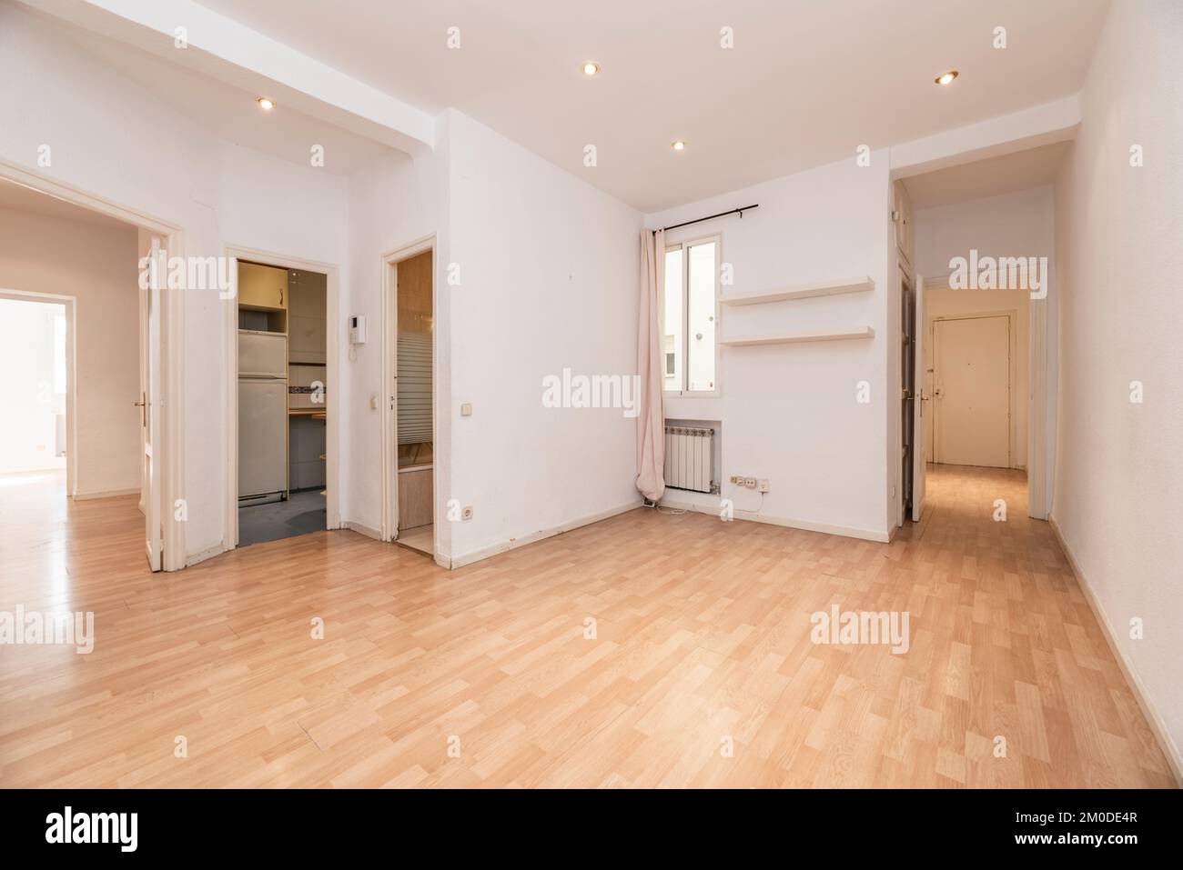 Leeres Wohnzimmer eines Hauses mit Zugang zu mehreren Zimmern, Holzboden und schmale weiße Aluminiumfenster Stockfoto