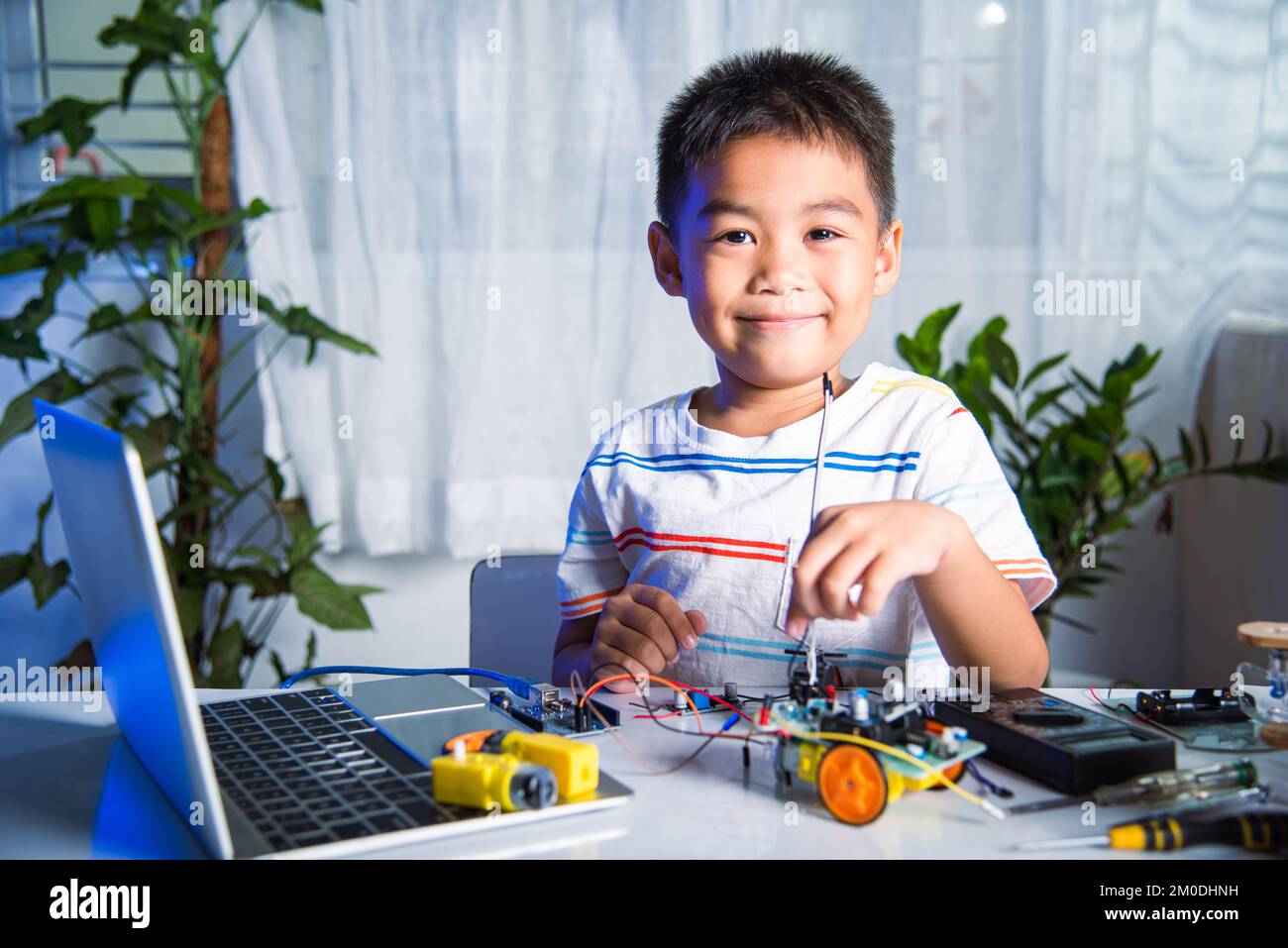 Asiatischer Junge stecken Energie-und Signalkabel an Sensor-Chip mit Arduino Roboterauto Stockfoto