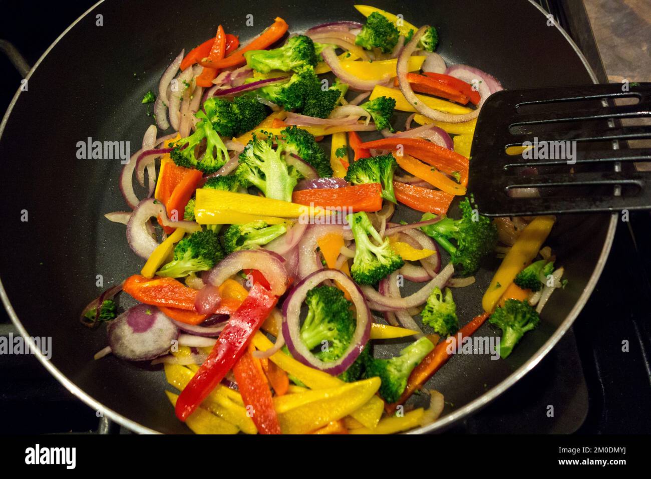 Bunte Gemüsebrühe mit Brokkoli, roten Zwiebeln und Paprika. Kochen Sie eine gesunde pflanzliche Mahlzeit in einer Pfanne. Stockfoto
