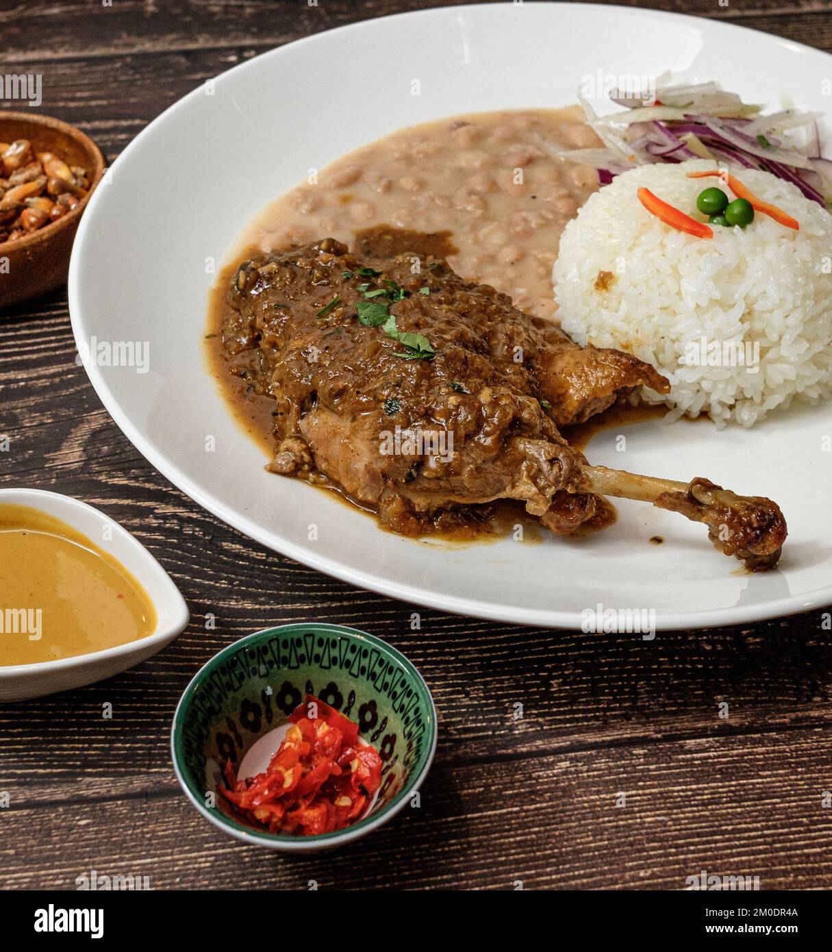 Weiße Bohnen mit Hähnchen und Rindfleisch, serviert mit Reis und roten Zwiebeln gewürzt Stockfoto