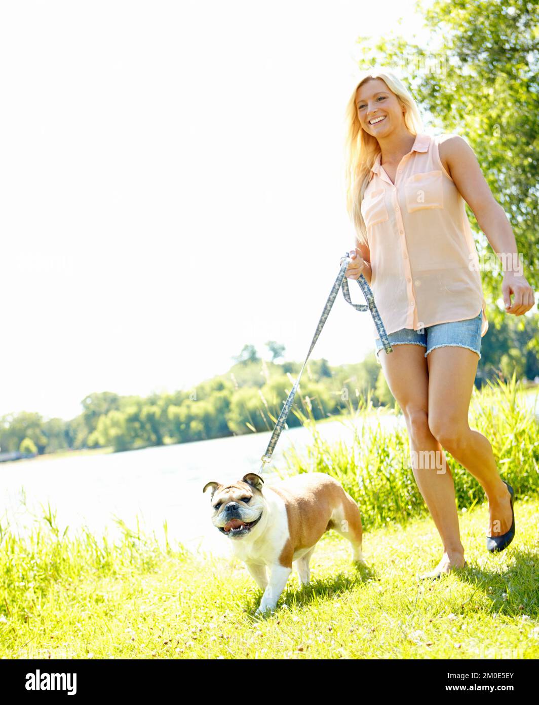 Wir gehen jeden Tag spazieren. Eine schöne Blondine, die mit ihrem Hund spazieren geht. Stockfoto