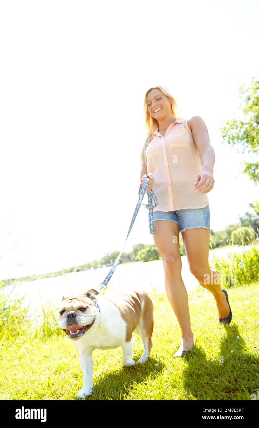 Frische Luft schnappen und Sport treiben. Eine schöne Blondine, die mit ihrem Hund spazieren geht. Stockfoto