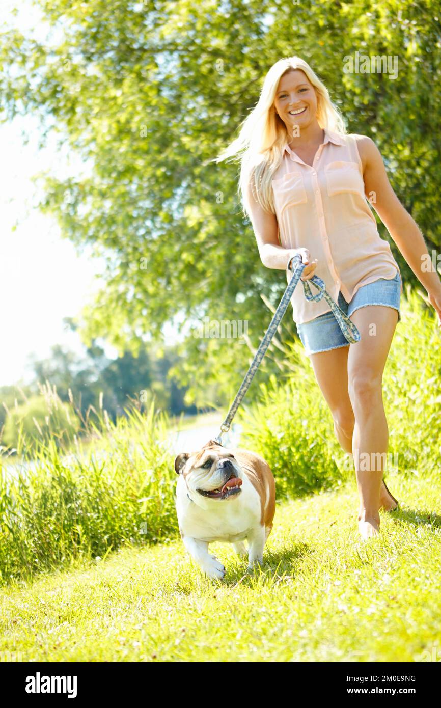 Wir bekommen beide unsere tägliche Bewegung. Eine schöne Blondine, die mit ihrem Hund spazieren geht. Stockfoto