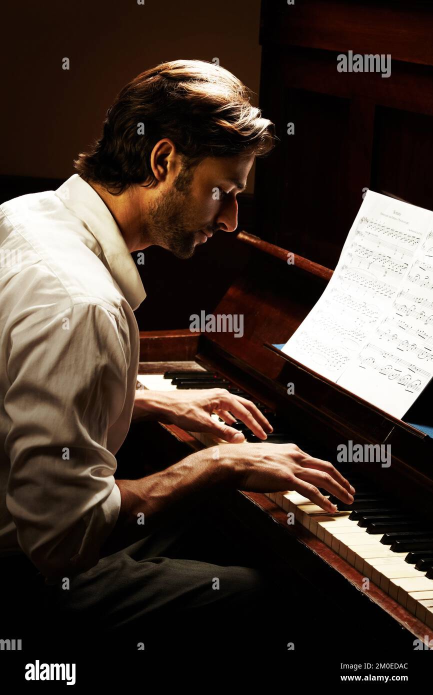 Schöne Musik machen. Profil eines hübschen Mannes, der Klavier spielt. Stockfoto