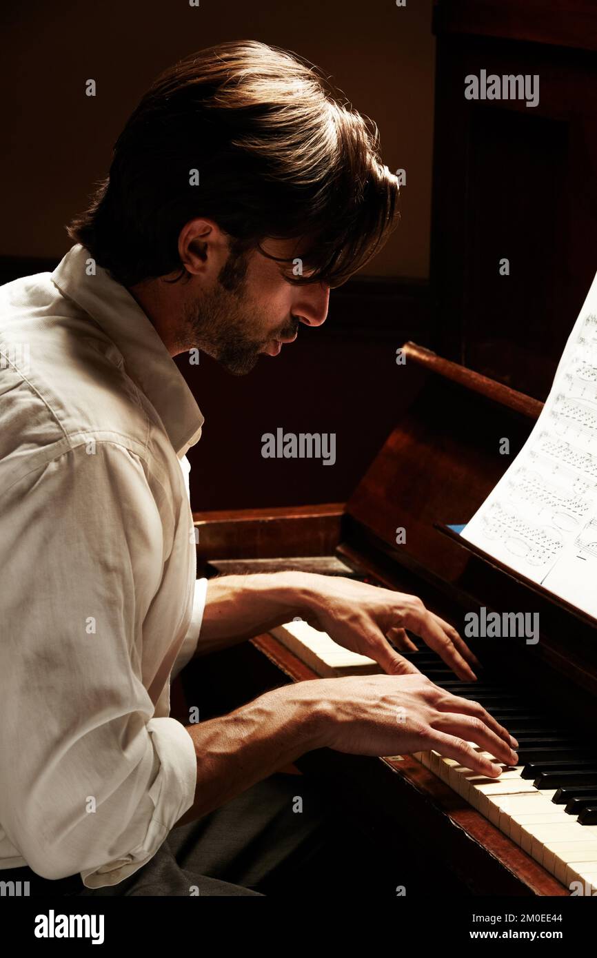 Schöne Musik machen. Profil eines hübschen Mannes, der Klavier spielt. Stockfoto