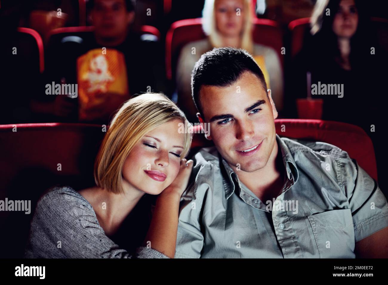 Er ist ihr Prinz Charming. Eine glückliche junge Frau kuschelt bei ihrem Date im Kino mit ihrem Freund. Stockfoto