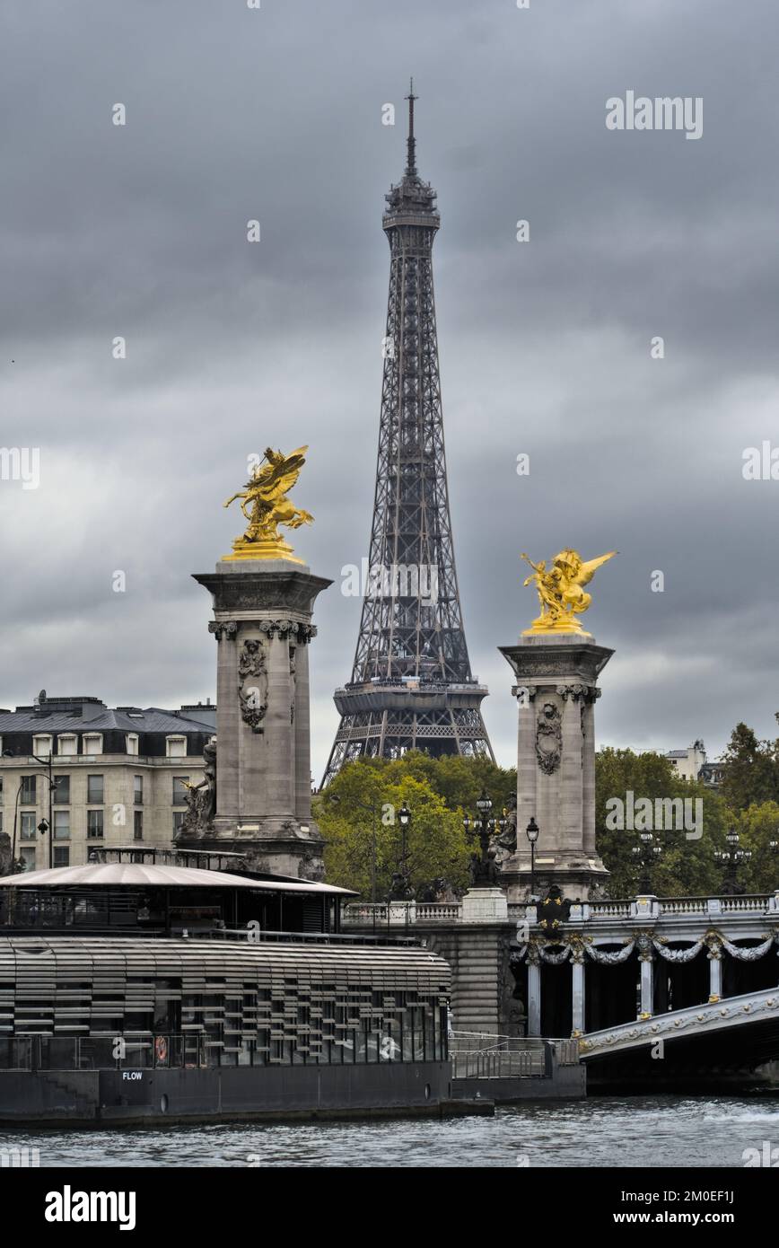 Eiffelturm mit den goldenen Statuen auf der Brücke Pont Alexandre III in Paris an einem bewölkten Tag. Stockfoto