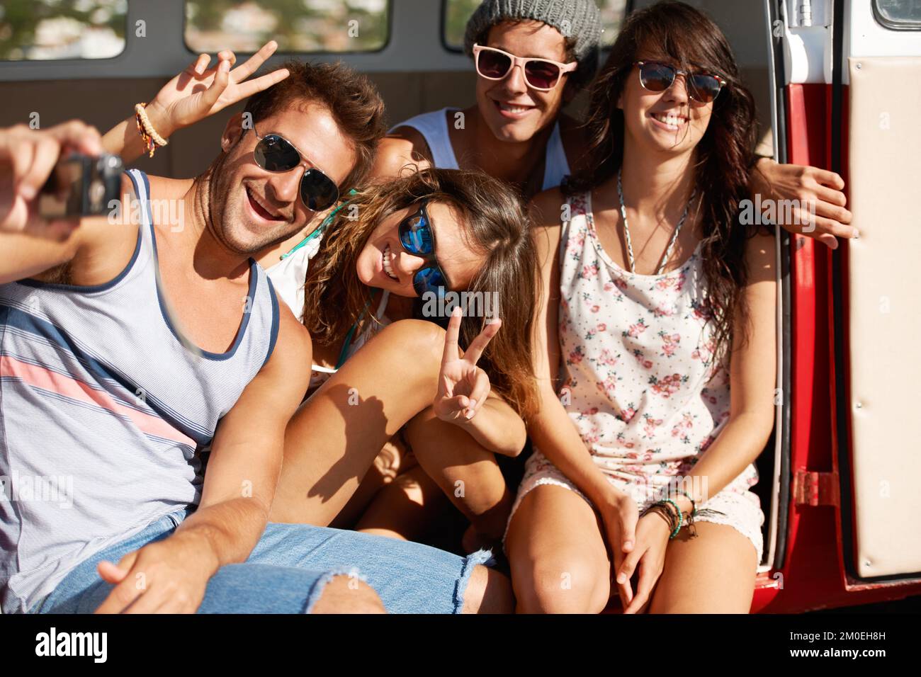 Freunde für immer. Vier Freunde, die in der Sommersonne um ein Schnappschuss-Foto herumspielen. Stockfoto