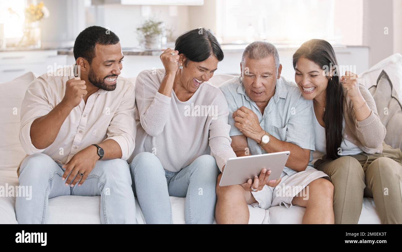 Familienfeiern mit gemischten Rassen, während Sie Sport auf einem Tablet ansehen und zu Hause auf dem Sofa in der Lounge sitzen. Die hispanische Familie sieht begeistert aus Stockfoto