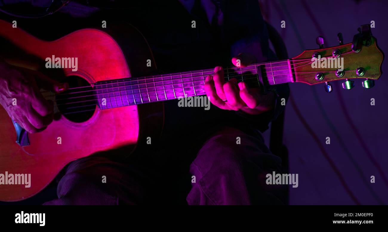 Nahaufnahme männliche Hände spielen Gitarre auf der Bühne live in einem Konzert mit Neonlichtern. Stockfoto