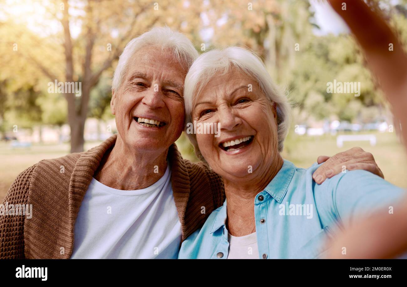Liebe, Lächeln und Selfie mit dem alten Paar im Park, um sich zu verbinden, zu entspannen und Zuneigung zu haben. Ruhestand, Natur und glücklich mit dem Porträt von Mann und Frau Stockfoto