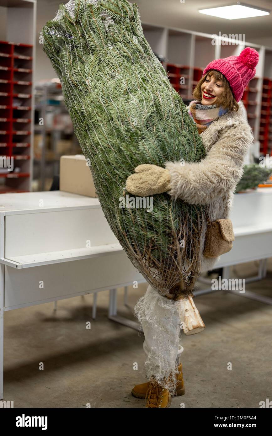 Glückliche Frau holt Weihnachtsbaum bei der Post ab Stockfoto