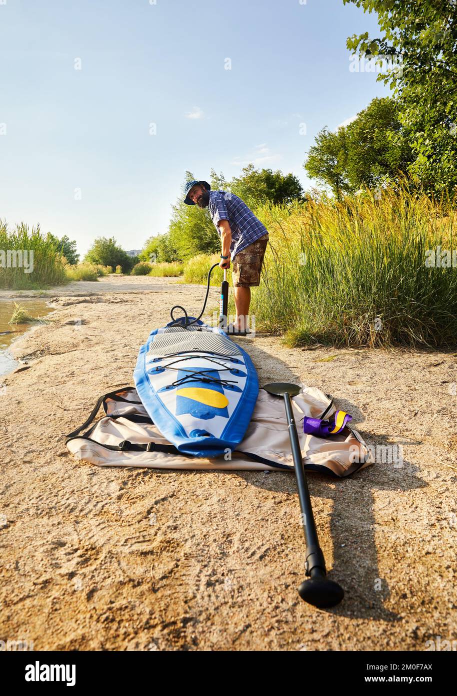 Man pumpt Stand-Up-Paddle-Boards SUP am Strand des Sees Sairan in der Stadt Almaty in Kasachstan. Stockfoto