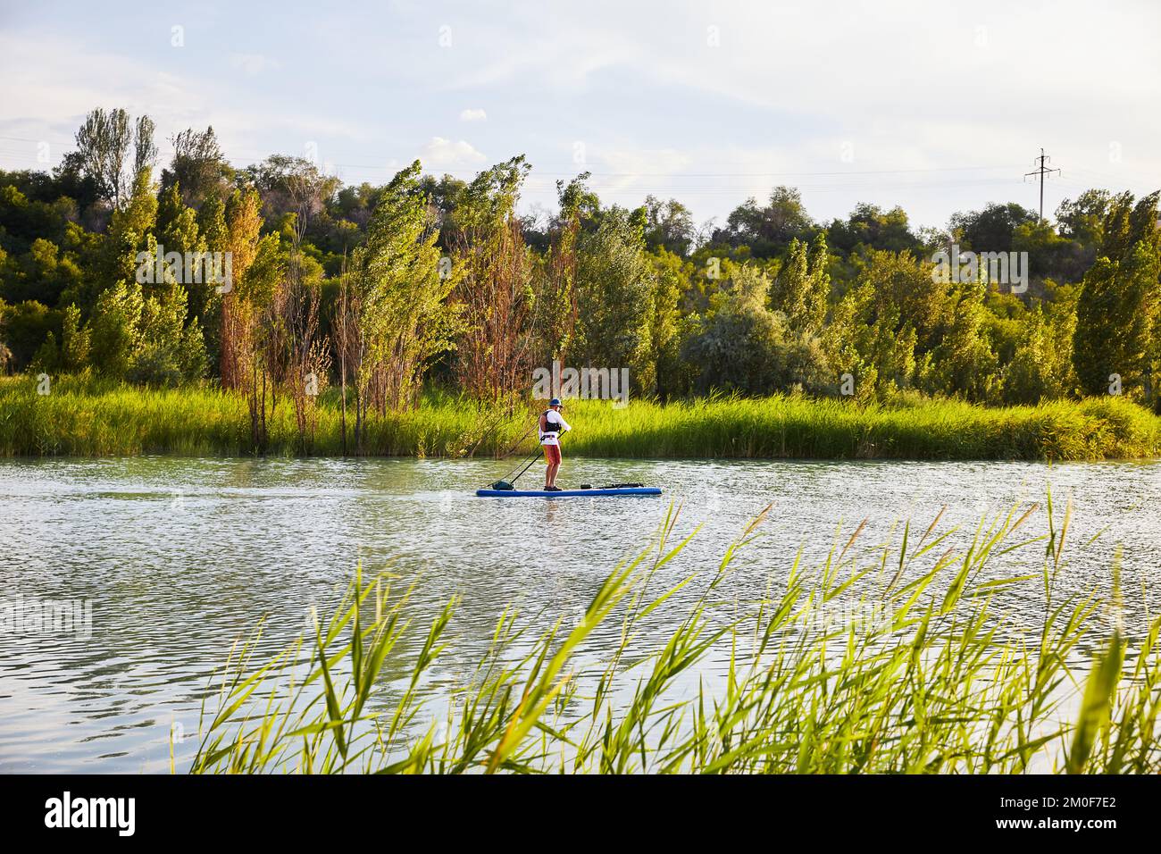 Mann an Stand-Up-Paddle-Boards SUP im Bergsee Sairan in der Stadt Almaty in Kasachstan. Stockfoto