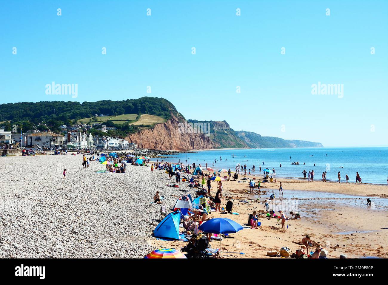 Touristen entspannen sich am Strand mit Blick auf die Stadt und die Klippen, Sidmouth, Devon, Großbritannien, Europa. Stockfoto