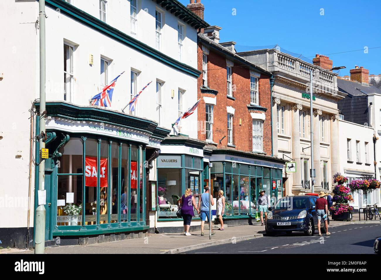 Blick auf die Einkaufsstraße High Street im Stadtzentrum mit Shoppers zu Fuß, Sidmouth, Devon, Großbritannien, Europa. Stockfoto