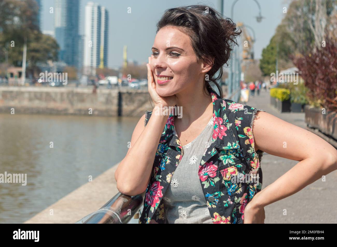 Erwachsene, weiße Touristenfrau, die sich auf einem Geländer vor dem Deich in Buenos Aires lehnt, lächelt, blickt in die Ferne und denkt, wo Stockfoto