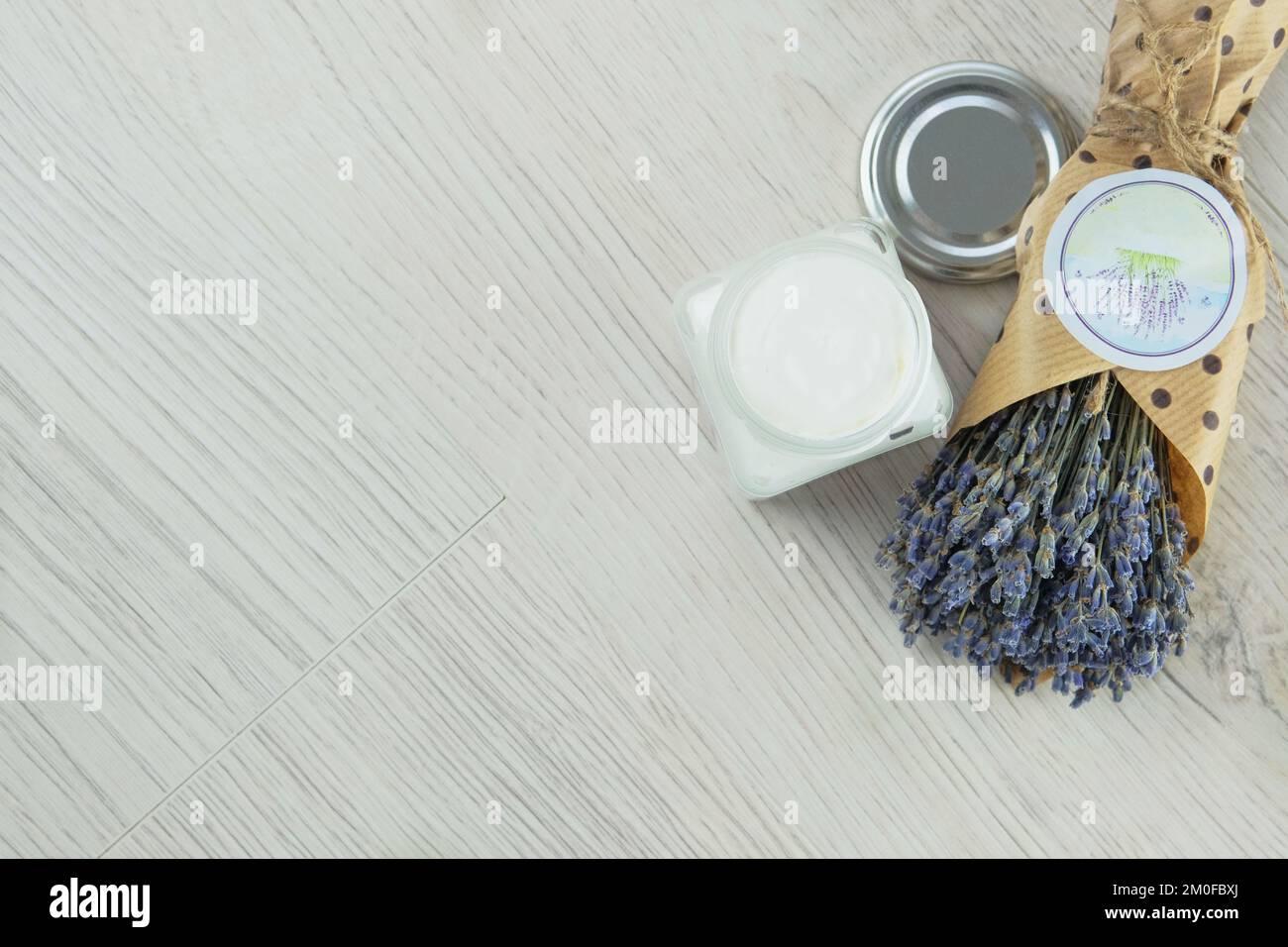 Handgefertigte kosmetische Cremebecher und getrocknete Lavendelblumen auf hellem Hintergrund. Bio-organische Kosmetik. Stockfoto