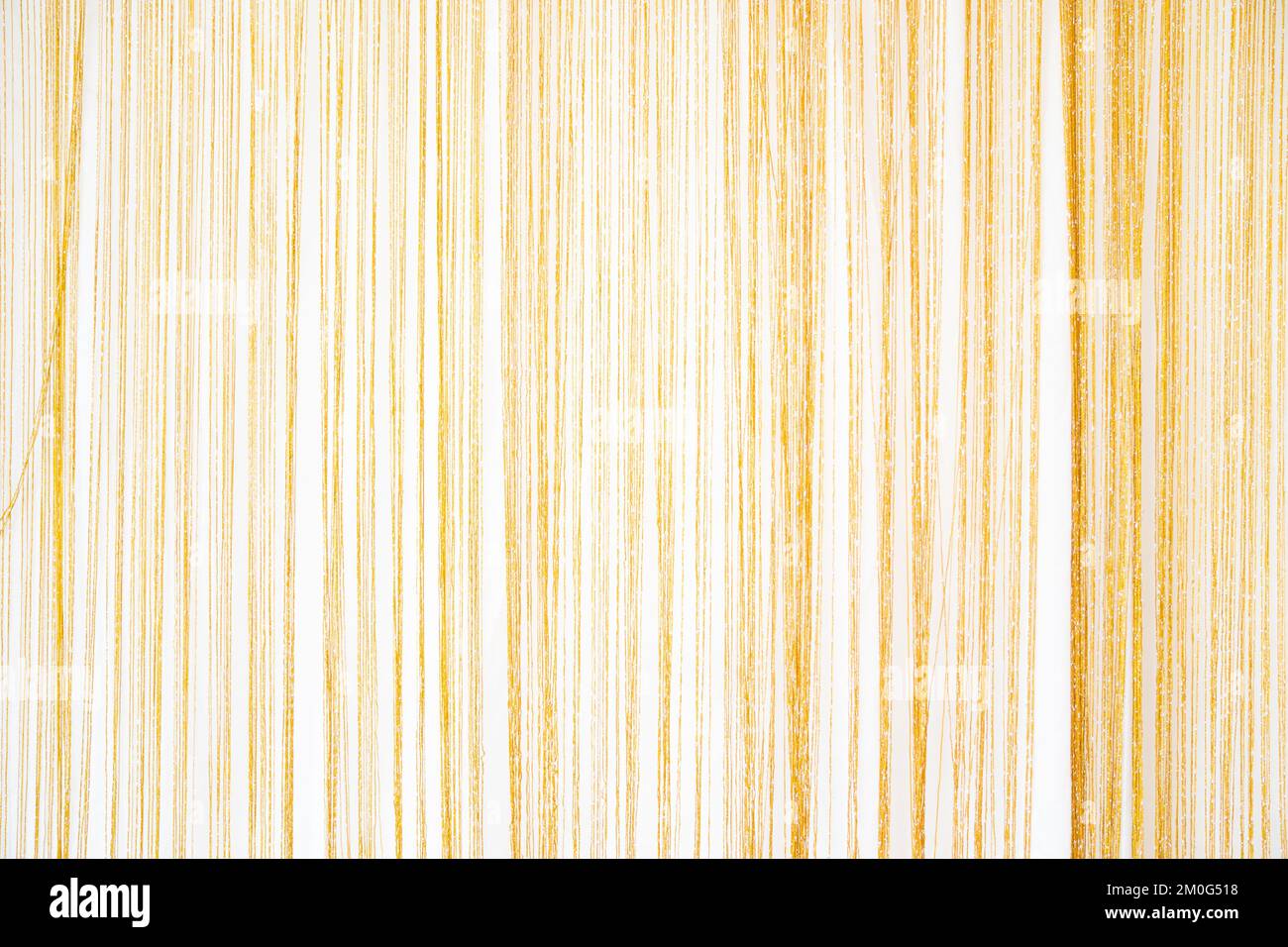 Dünnes goldenes Seidengarn, das in jeder Zeile fein angeordnet ist, ein stilvoller Vorhang, der als schöne Kulisse für Fotografie geeignet ist. Stockfoto