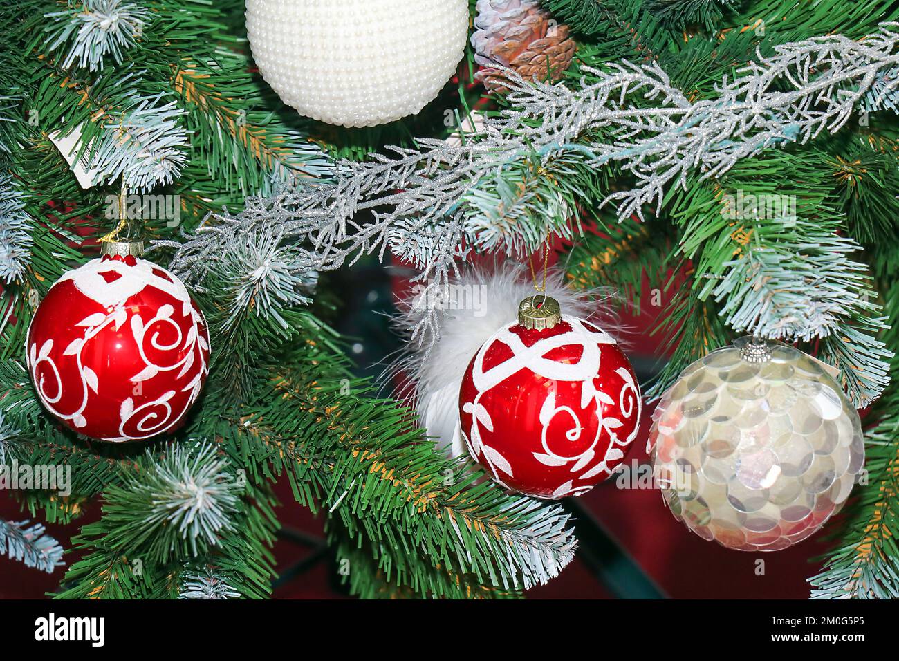 Festliche Weihnachtsbaumschmuck, die an einem grünen Ast hängen Stockfoto
