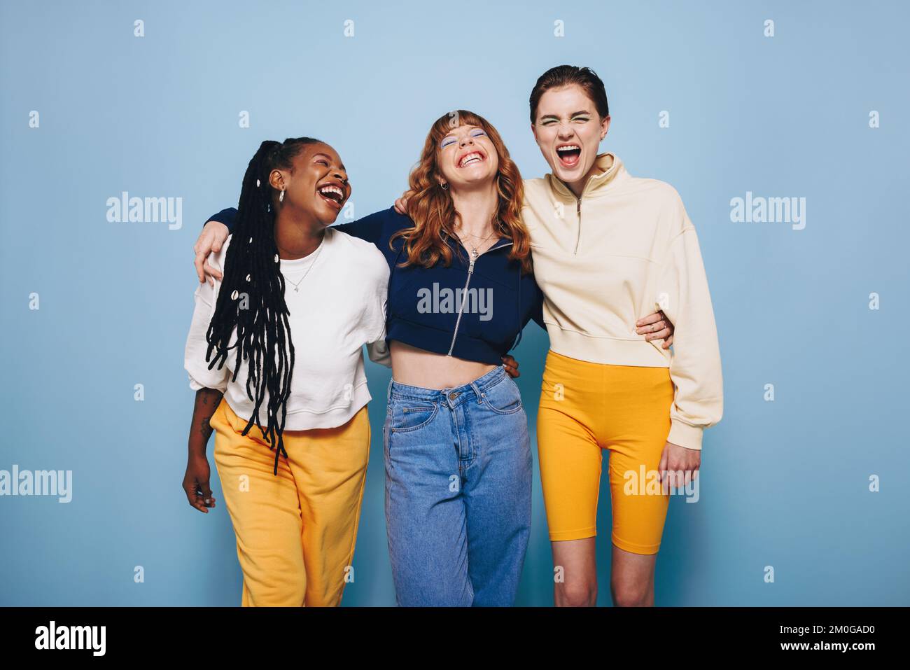 Drei beste Freunde lachen und amüsieren sich, während sie sich in einem Studio umarmen. Eine Gruppe glücklicher Freundinnen, die sich amüsieren Stockfoto