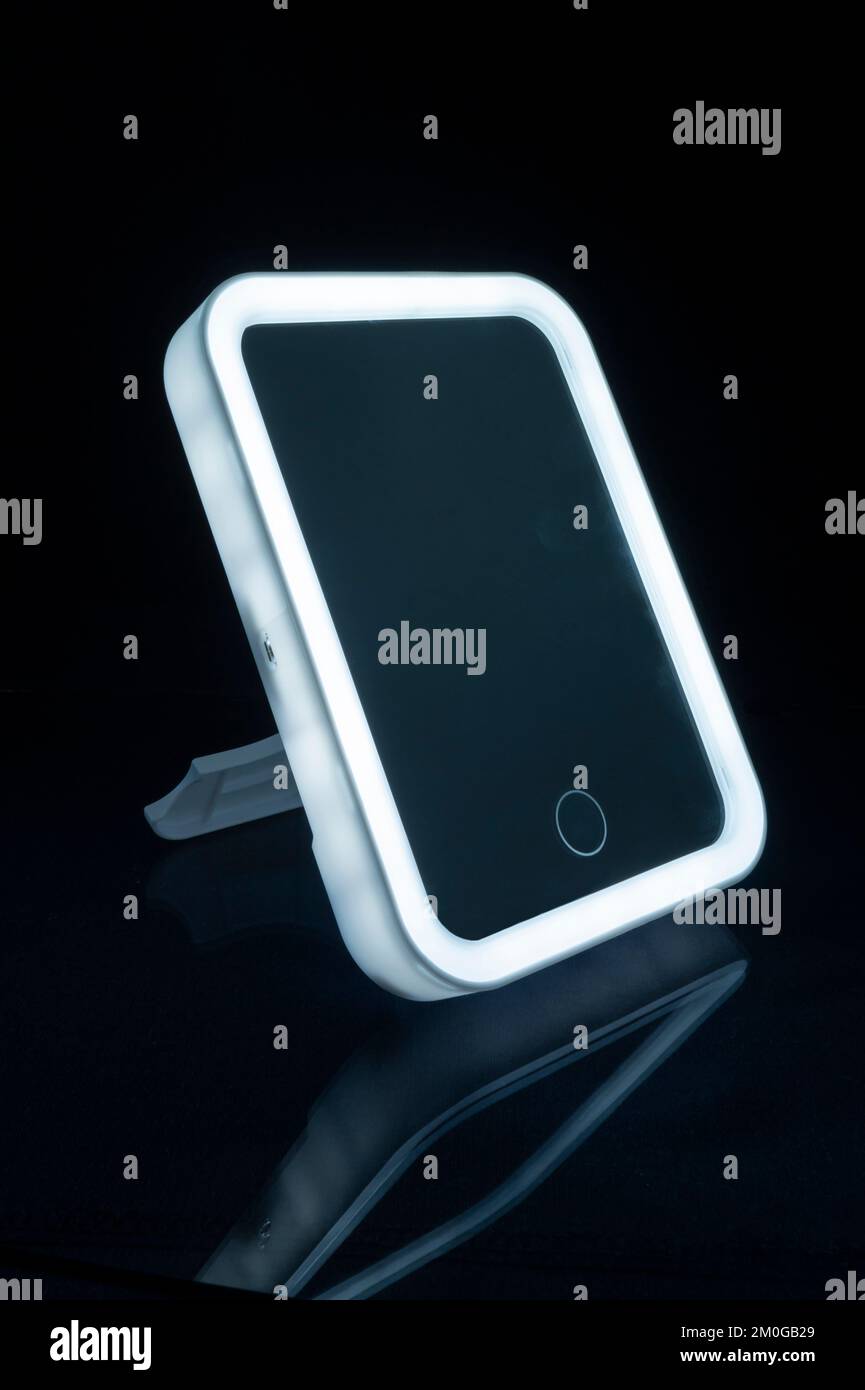 Der Spiegel wird entlang der Kontur beleuchtet. Haushaltsgegenstände auf schwarzem Hintergrund Stockfoto