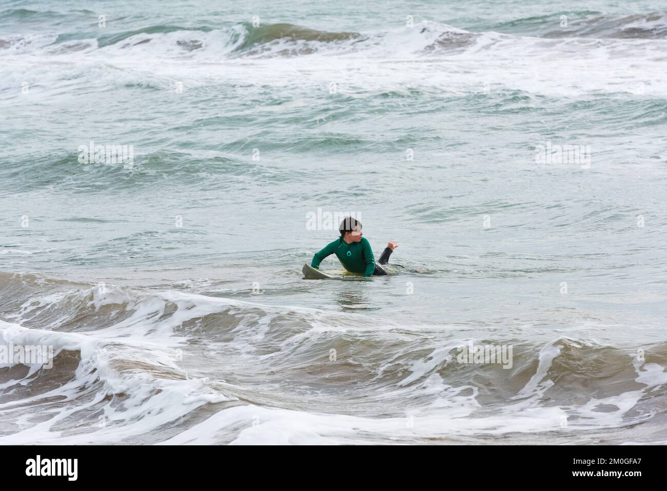 Castelldefels, Barcelona, Spanien - 9. Januar 2016: Ein Junge zwischen 10 und 12 Jahren surft allein am Ufer, an einem kalten und bewölkten Wintertag Stockfoto