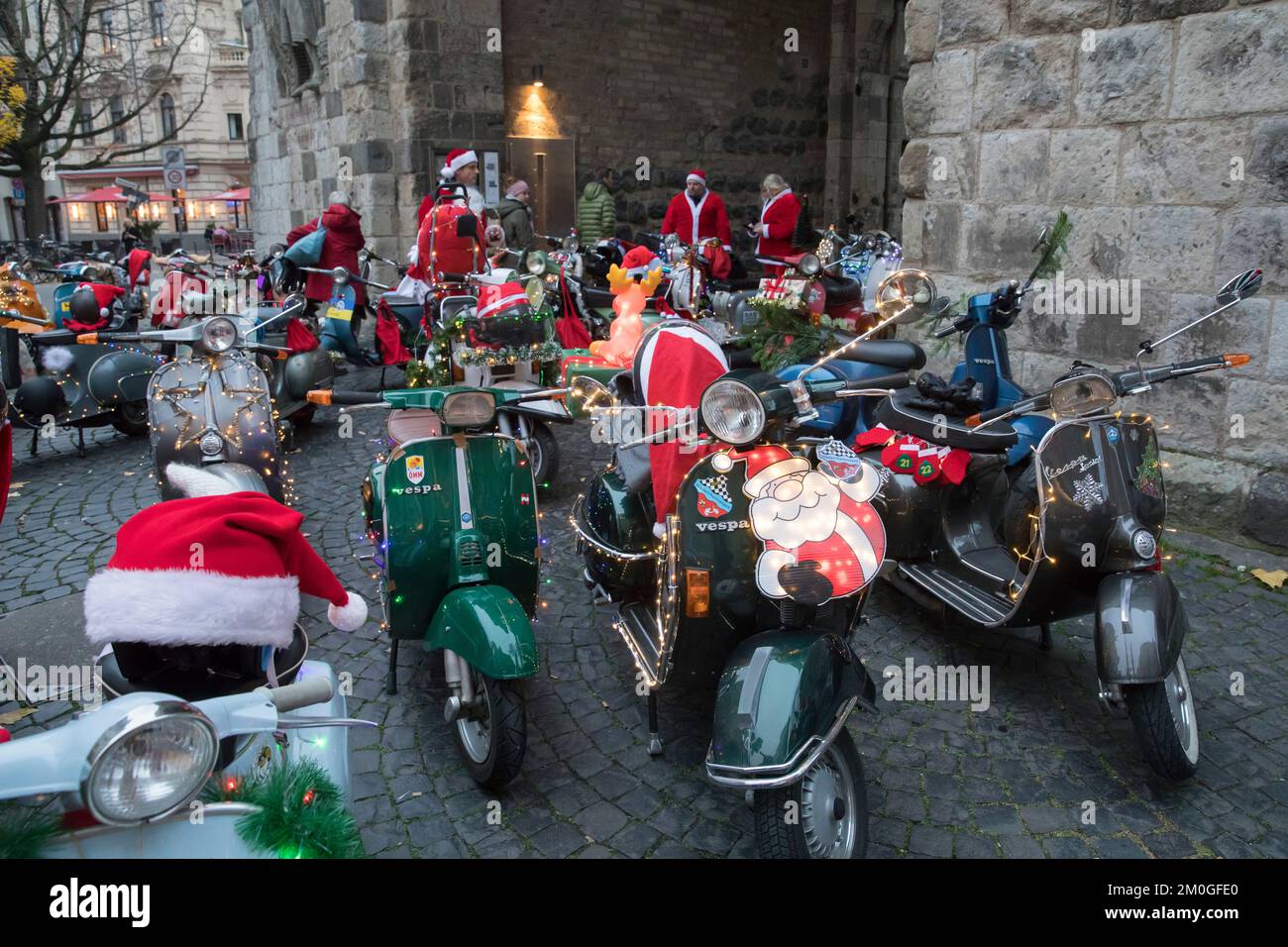 Mitglieder der Vespa-Motorroller-Clubs, die sich während einer Fahrt durch die Stadt Köln als Santas verkleidet haben. Die Roller sind beleuchtet und für Chri dekoriert Stockfoto