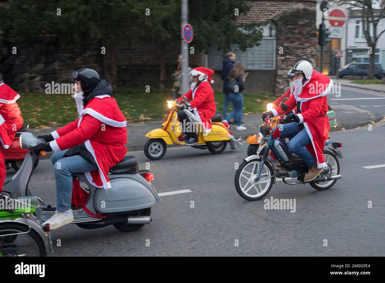 Mitglieder der Vespa-Motorroller-Clubs, die sich während einer Fahrt durch  die Stadt Köln als Santas verkleidet haben. Die Roller sind beleuchtet und  für Chri dekoriert Stockfotografie - Alamy