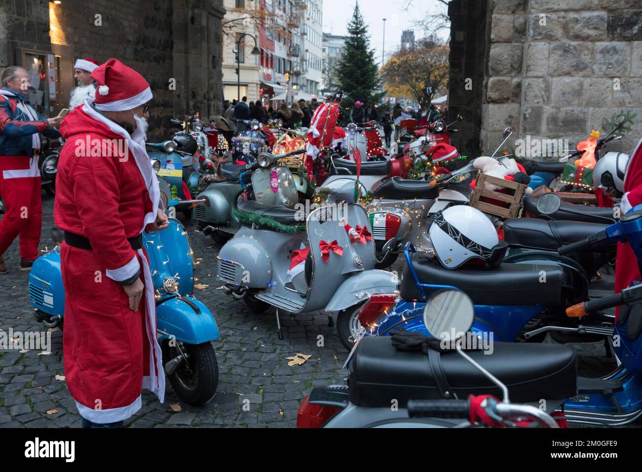 Mitglieder der Vespa-Motorroller-Clubs, die sich während einer Fahrt durch die Stadt Köln als Santas verkleidet haben. Die Roller sind beleuchtet und für Chri dekoriert Stockfoto