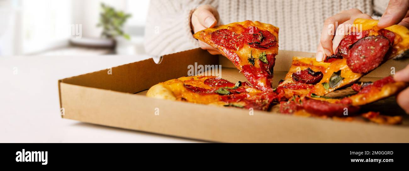 Hände, die Pizzastücke aus der Schachtel nehmen. Partysnacks. Banner mit Kopierbereich Stockfoto