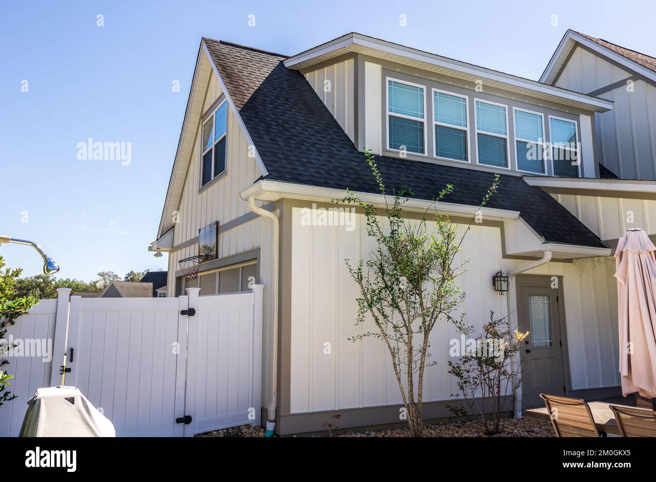 Die Seitenansicht eines langen Handwerkerhauses in weißem cremefarbenen Neubau mit überdachtem Terrassenbereich Stockfoto