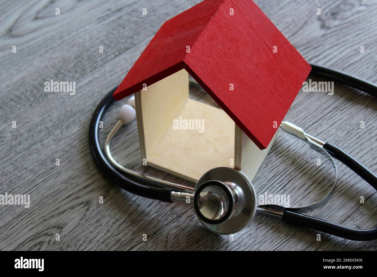 Stethoskop und Haus auf Holztisch. Hausinspektion, Reparatur und Diagnosekonzept Stockfoto
