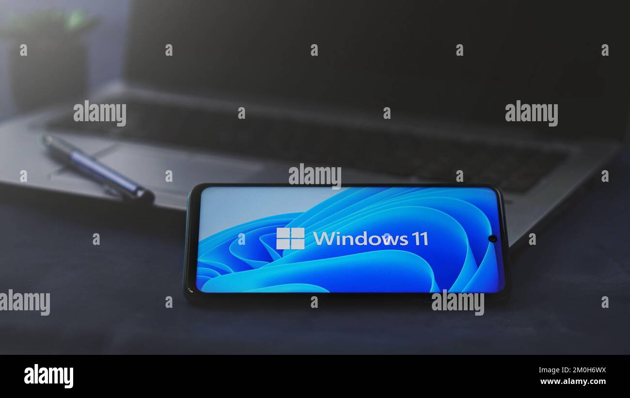 Dobrich, Bulgarien – 2022, November 26: Mobiltelefon auf einem Laptop mit dem Microsoft-Logo und Windows 11. Anschauliches Editorial-Konzept für Software Stockfoto