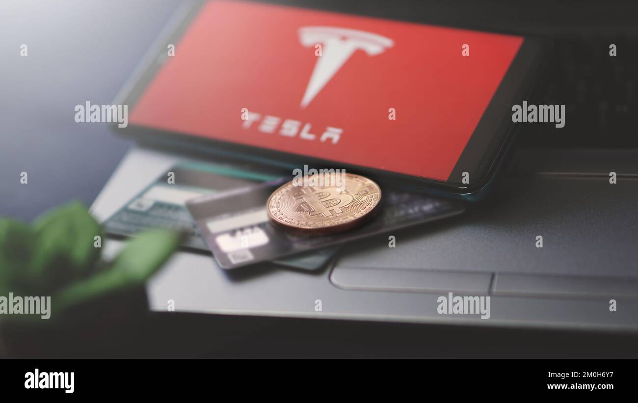 Dobrich, Bulgarien – 2022. November 26: Mobiltelefon auf einem Laptop mit Tesla Logo, Bitcoin und Kreditkarten. Anschauliches Editorial-Konzept Stockfoto