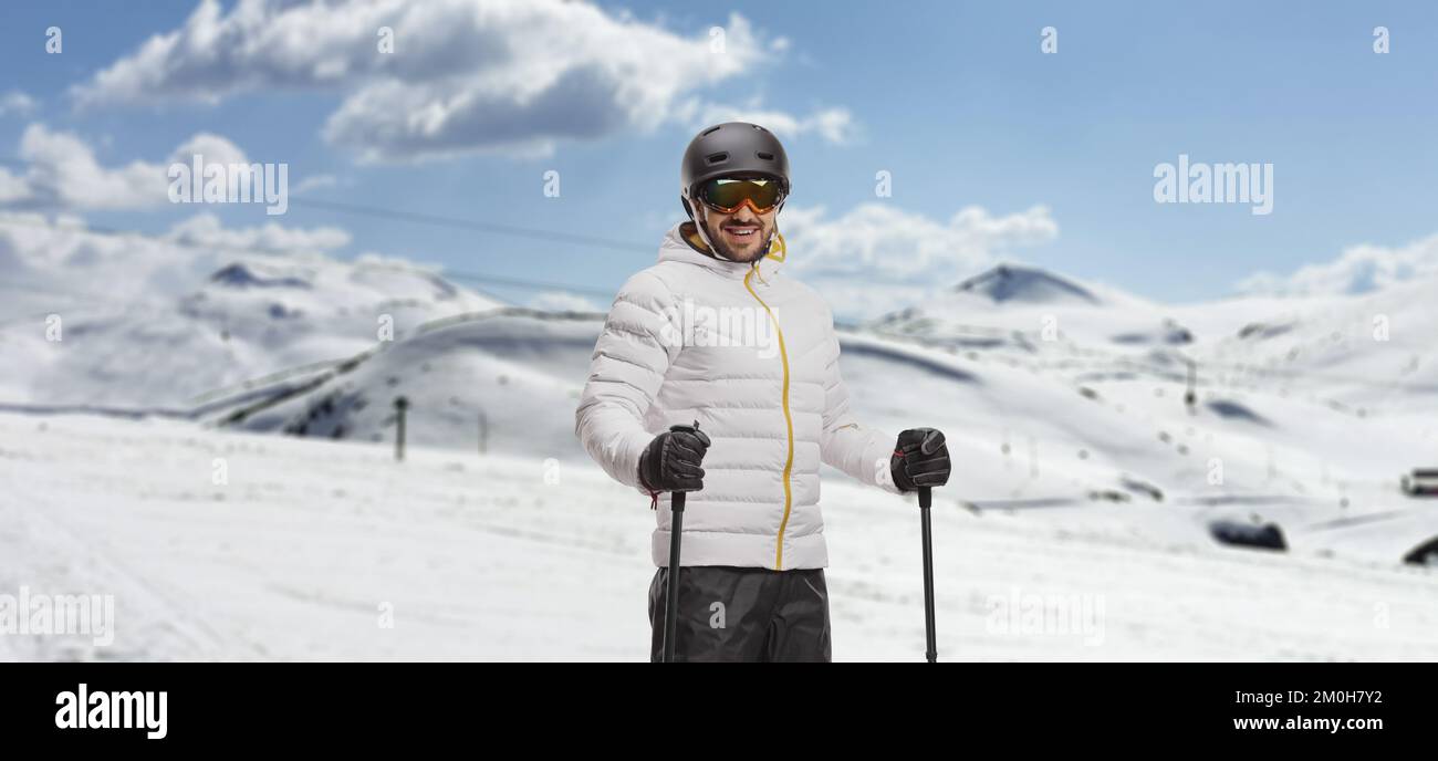 Ein Mann mit Skiern posiert in einem Skigebiet Stockfoto