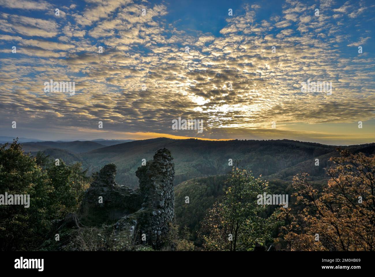 Herbstlandschaft bei Sonnenuntergang mit der Mauer der Burgruine. Wunderschöner blauer Himmel, Wolkenansammlung... Schutzgebiet Vrsatec, Slowakei. Stockfoto